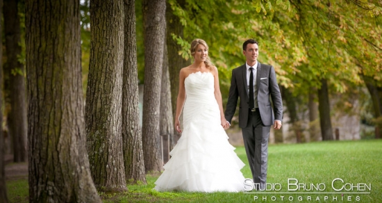 mariage naturel , mariés qui marchent main dans la main le long de l'allée d'arbre devant le Chateau de Chantilly
