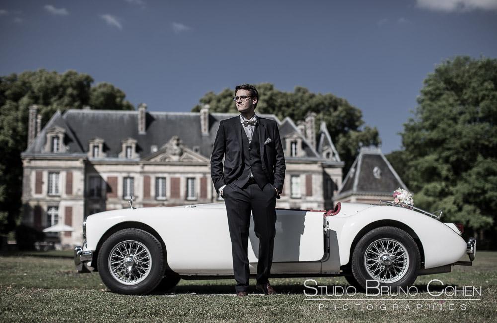 marié debout devant une voiture décapotable blanche au chateau de saint-remy-en-l'eau