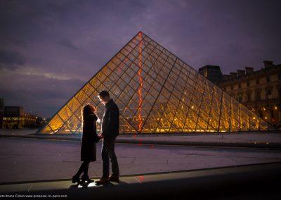 a couple in front of the Louvre Pyramid at twilight Paris