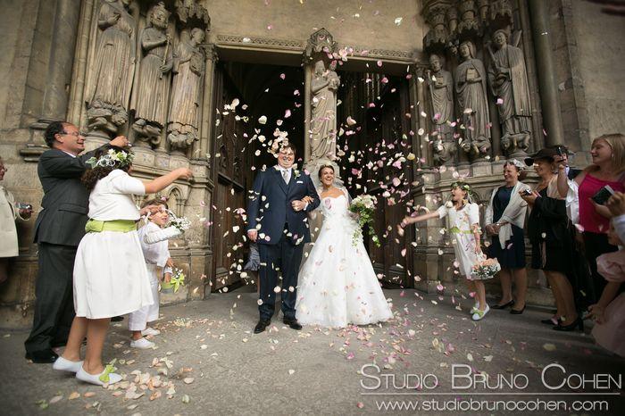couple de mariés sous les confettis à la sortie d'une messe de mariage à l'église Saint Germain L'Auxerrois Paris