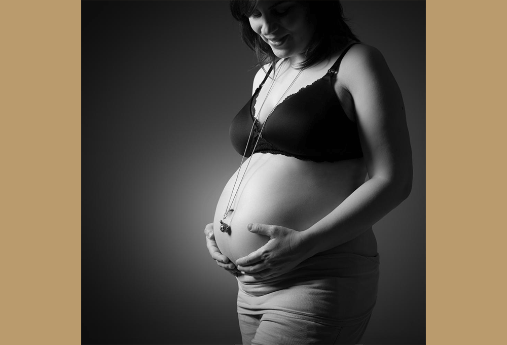Shooting photo famille : femme enceinte en soutien-gorge soutenant son ventre